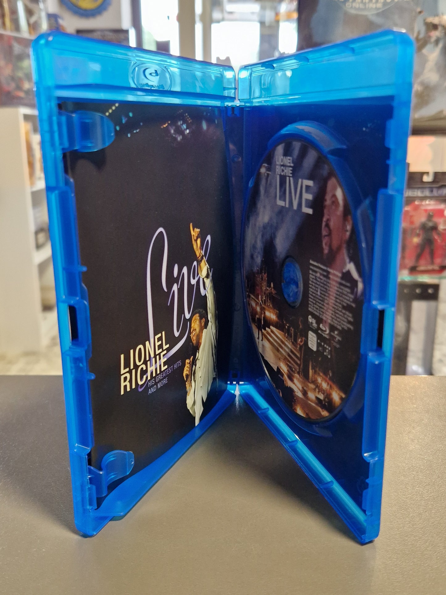 Geöffnete blaue Blu-ray Hülle von Lionel Richie Live mit der bedruckten Konzert-Disc auf der rechten Seite und dem farbigen Begleit-Inlay auf der linken Seite.