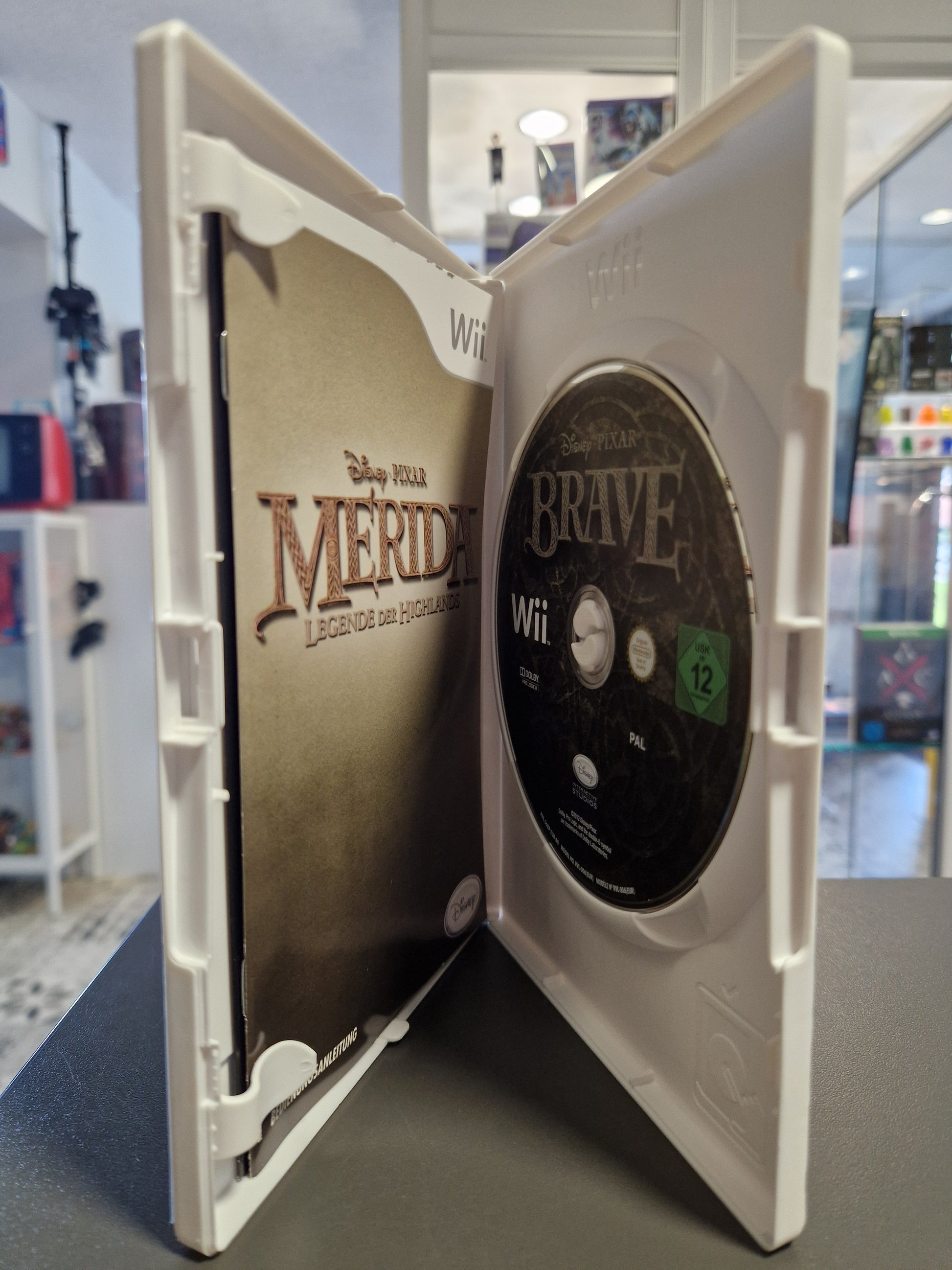 Geöffnete Nintendo Wii Hülle von Merida Legende der Highlands mit der Spiele-Disc und der gedruckten Spielanleitung.