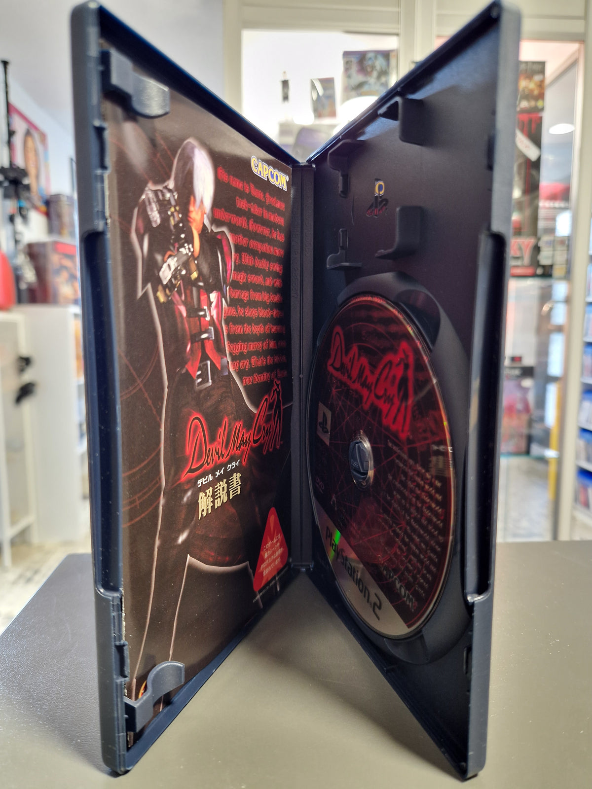 Geöffnete japanische PS2 Hülle von Devil May Cry mit Disc und Anleitungsheft.