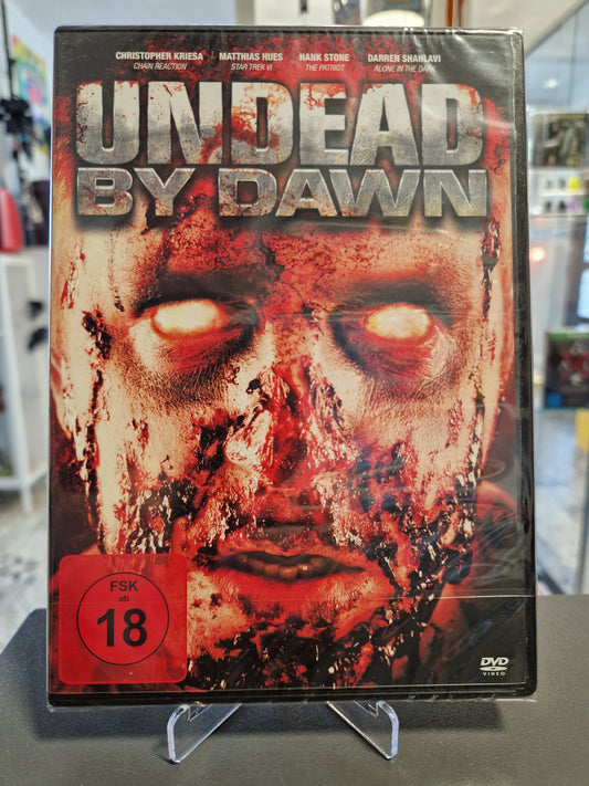 Originalverpackte und in Folie eingeschweißte DVD des Horrorfilms Undead by Dawn mit rotem FSK 18 Logo. Das Cover zeigt ein blutüberströmtes Zombiegesicht mit weiß leuchtenden Augen.