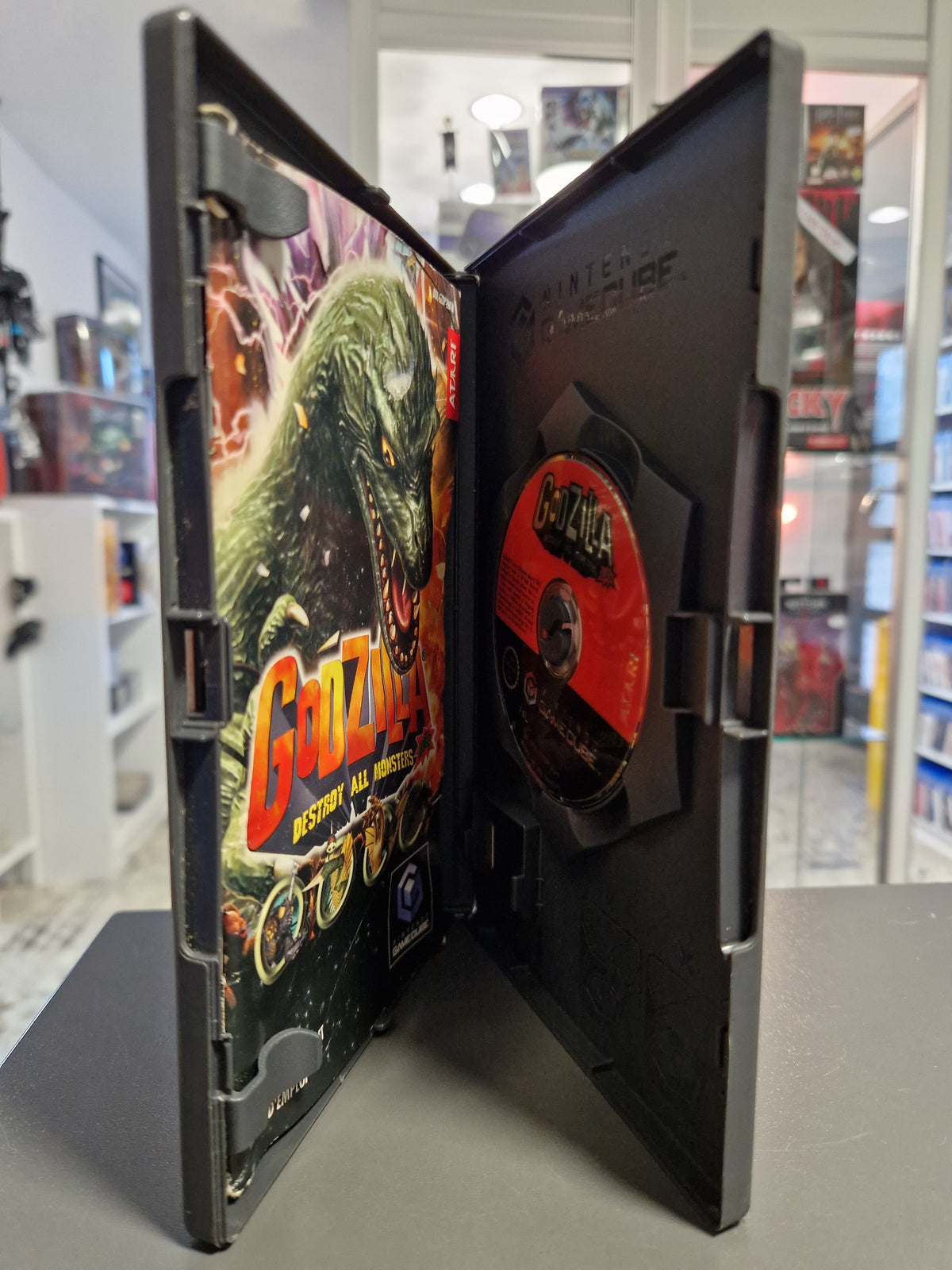 Geöffnete Nintendo GameCube Hülle von Godzilla mit Disc und deutscher Spielanleitung.