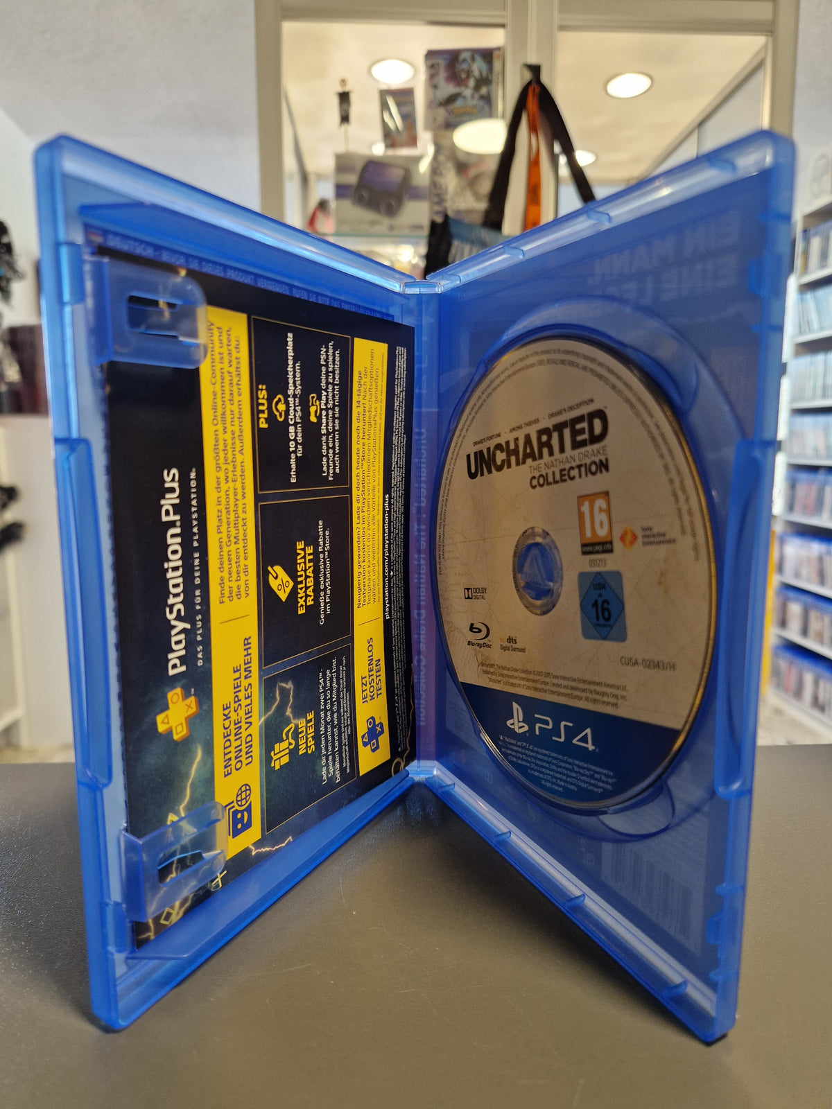 Geöffnete PS4 Hülle von Uncharted The Nathan Drake Collection mit Blu-ray Disc und PlayStation Plus Beilage
