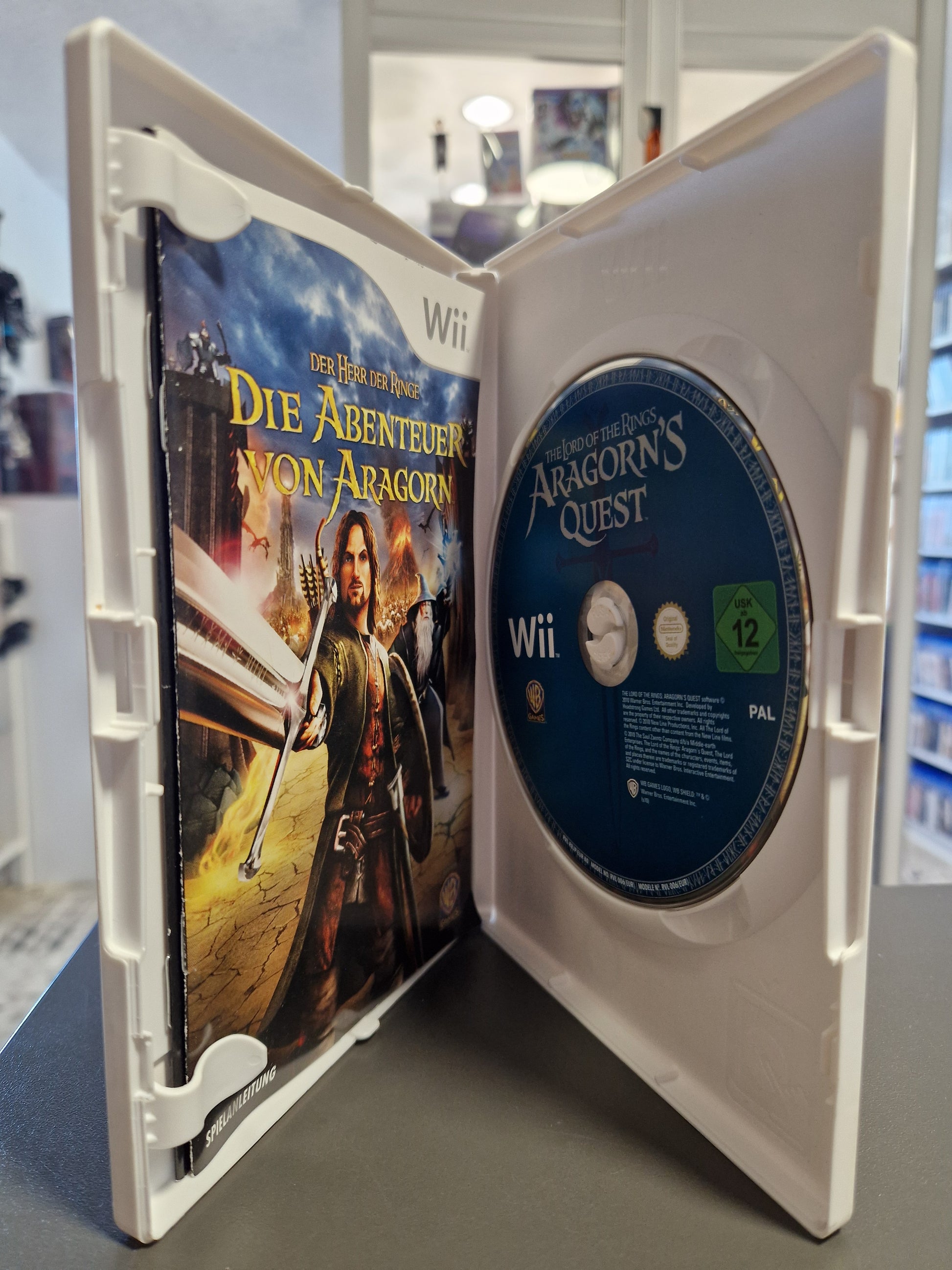 Geöffnete Nintendo Wii Hülle von Die Abenteuer von Aragorn mit der Spiele-Disc und der gedruckten Spielanleitung.