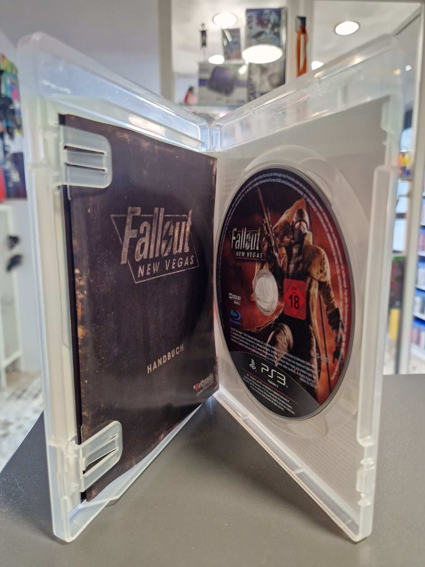 Die geöffnete PS3 Hülle zeigt das originale, dunkel gestaltete Fallout: New Vegas Handbuch auf der linken Seite und die saubere Spiele-Disc mit Ranger-Motiv auf der rechten Seite.