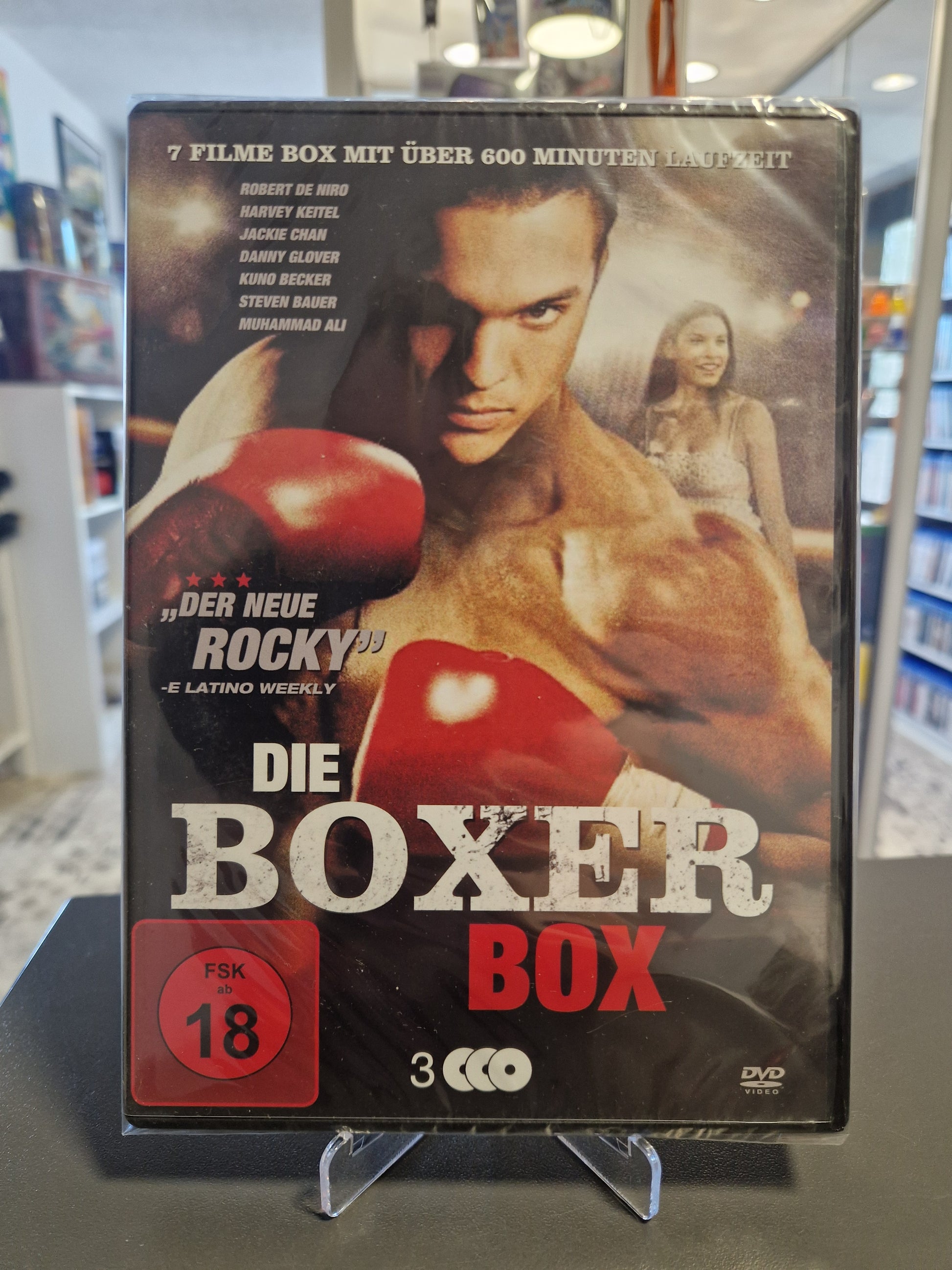 Neu und originalverpackte DVD-Sammlung Die Boxer Box mit FSK 18 Freigabe. Das Cover zeigt einen muskulösen Boxer mit roten Boxhandschuhen und listet Stars wie Robert De Niro, Jackie Chan und Muhammad Ali auf.