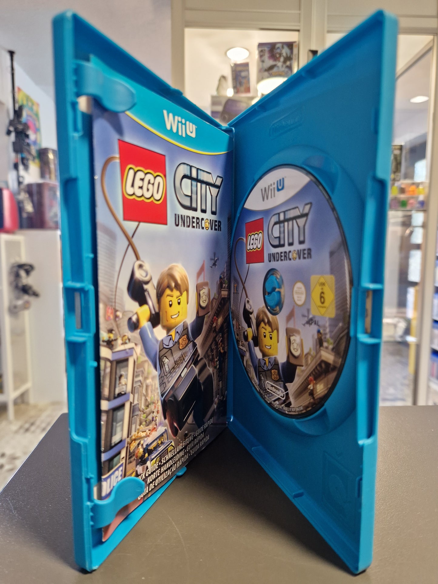 Geöffnete Wii U Hülle mit der Disc, der Anleitung und dem Informationsbeiblatt.