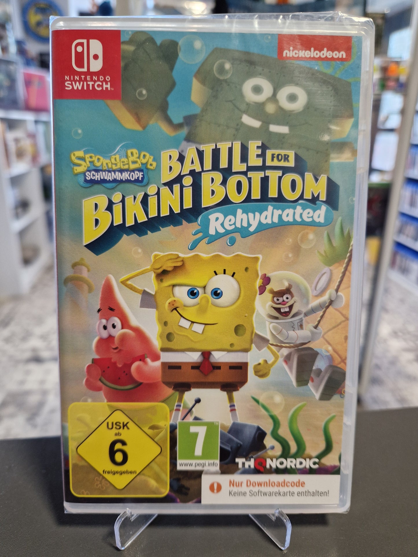Vorderseite der originalverpackten Switch Hülle von SpongeBob Schwammkopf: Battle for Bikini Bottom Rehydrated mit SpongeBob, Patrick, Sandy, gelbem USK 6 Logo und dem orangen Code in a Box Warnhinweis.