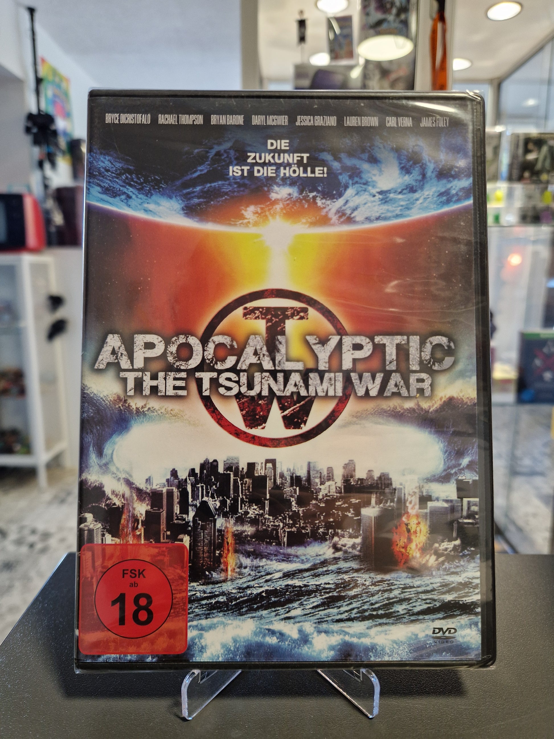 Neu und originalverpackte DVD des Endzeit-Films Apocalyptic: The Tsunami War mit rotem FSK 18 Logo. Das Cover zeigt eine gigantische Flutwelle über einer brennenden Großstadt und den Slogan Die Zukunft ist die Hölle.