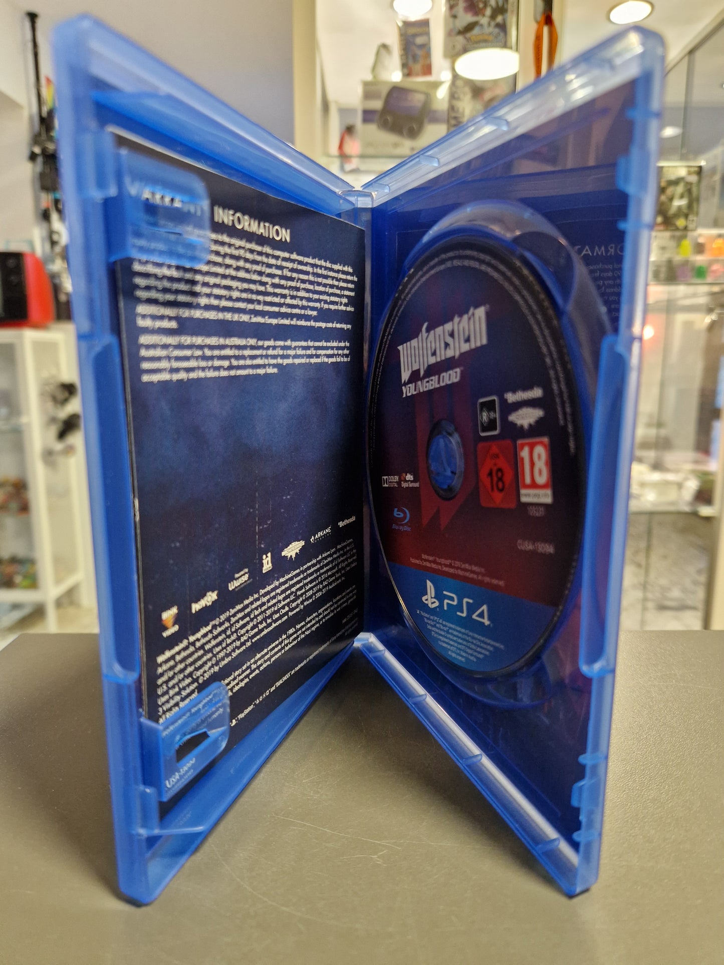 Blick in die geöffnete PS4-Hülle von Wolfenstein: Youngblood. Zu sehen ist die Blu-ray Disc im typischen Design und die Innenseite der Hülle mit Garantie-Informationen.