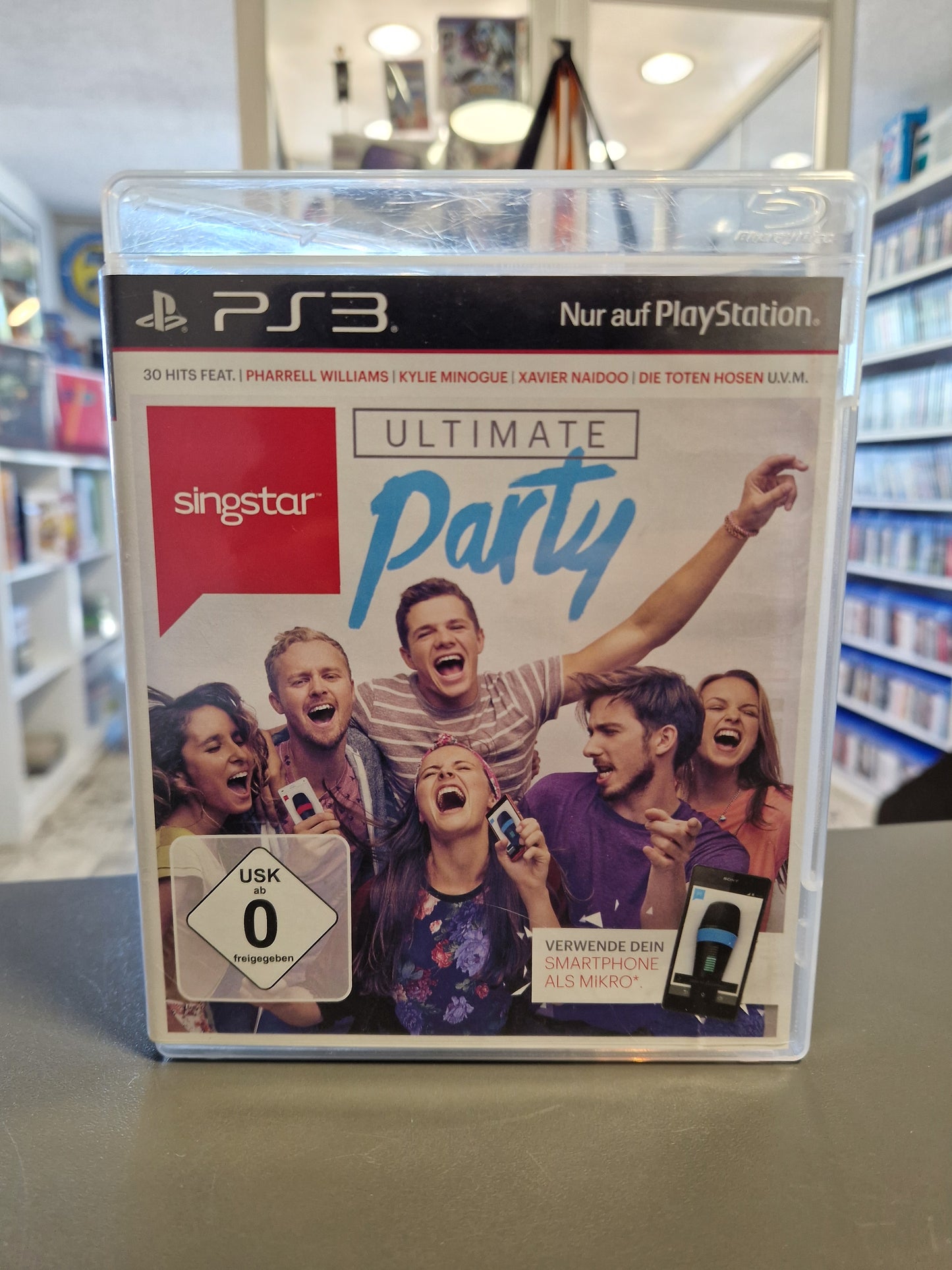 Die PlayStation 3 Spielehülle von SingStar: Ultimate Party. Auf dem Cover ist eine jubelnde Gruppe junger Leute beim Singen zu sehen. Unten links befindet sich das weiße USK 0 Logo.