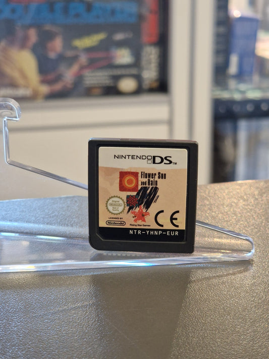 Nahaufnahme des Nintendo DS Spiele-Moduls „Flower, Sun, and Rain“ mit dem farbigen Logo-Etikett, platziert auf einem klaren Ständer.