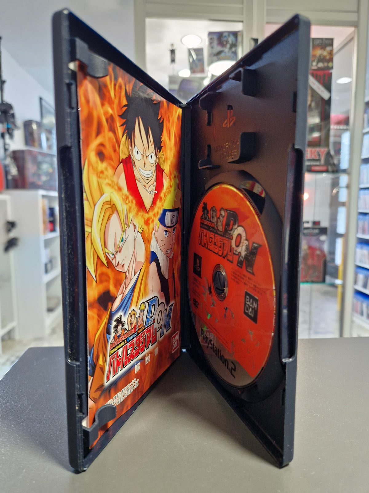Geöffnete PS2 Hülle von Battle Stadium D.O.N mit Disc und gedruckter japanischer Spielanleitung.
