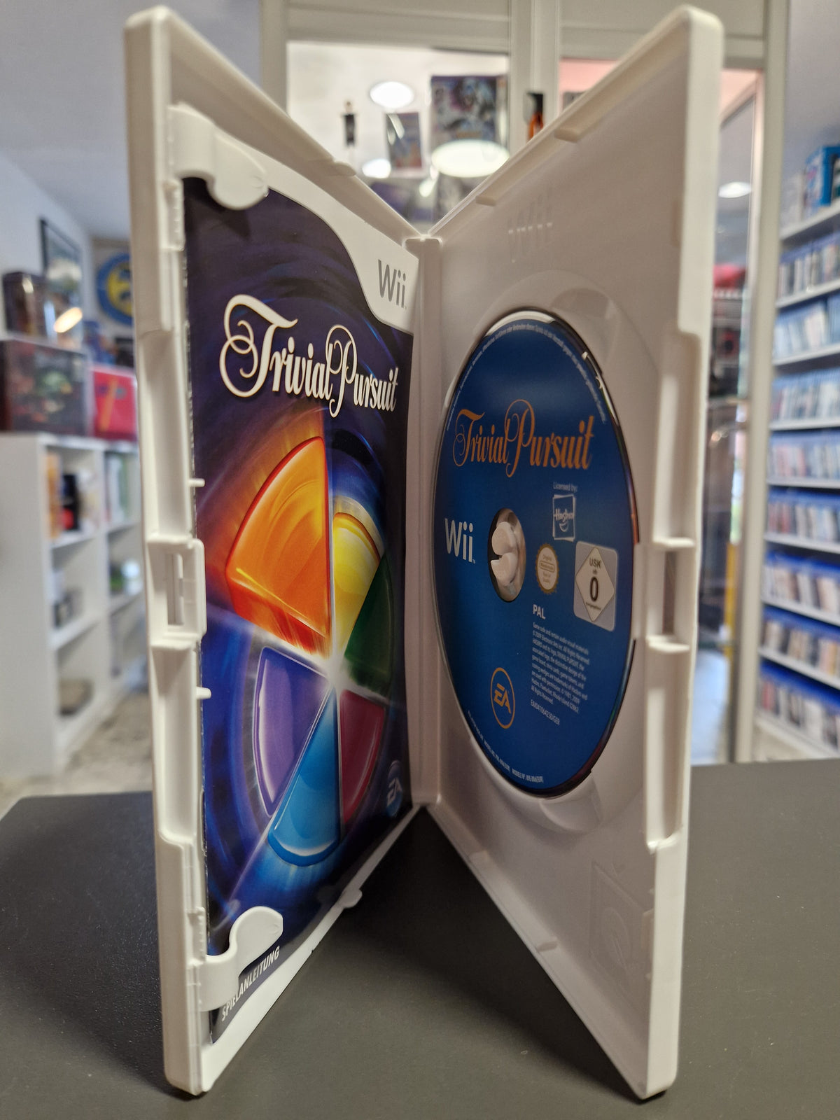 Geöffnete Nintendo Wii Hülle von Trivial Pursuit mit Disc und gedruckter Spielanleitung.