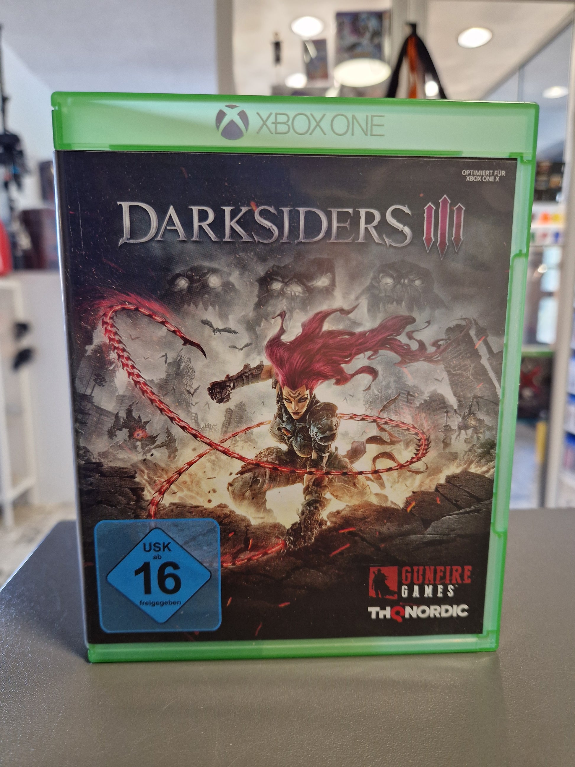 Vorderseite der Xbox One Hülle von Darksiders III mit Protagonistin Fury, Hinweis Optimiert für Xbox One X, THQ Nordic Logo und blaue USK 16 Kennzeichnung.