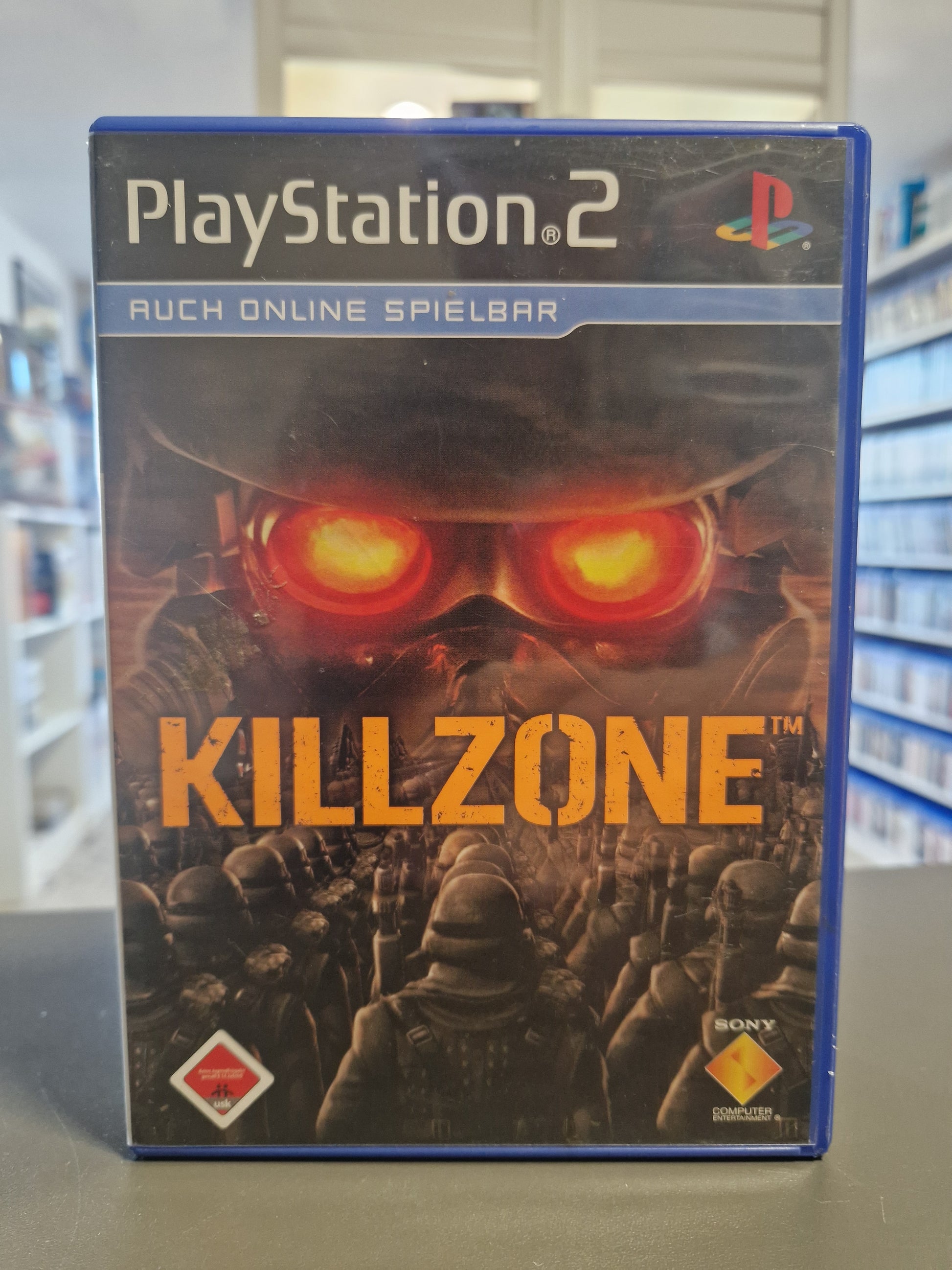 Das Foto zeigt das originale PlayStation 2 Cover von „Killzone“ im Hochformat mit dem bedrohlichen Gesicht eines Helghast-Soldaten mit rot leuchtenden Augen und einer marschierenden Armee im Vordergrund.