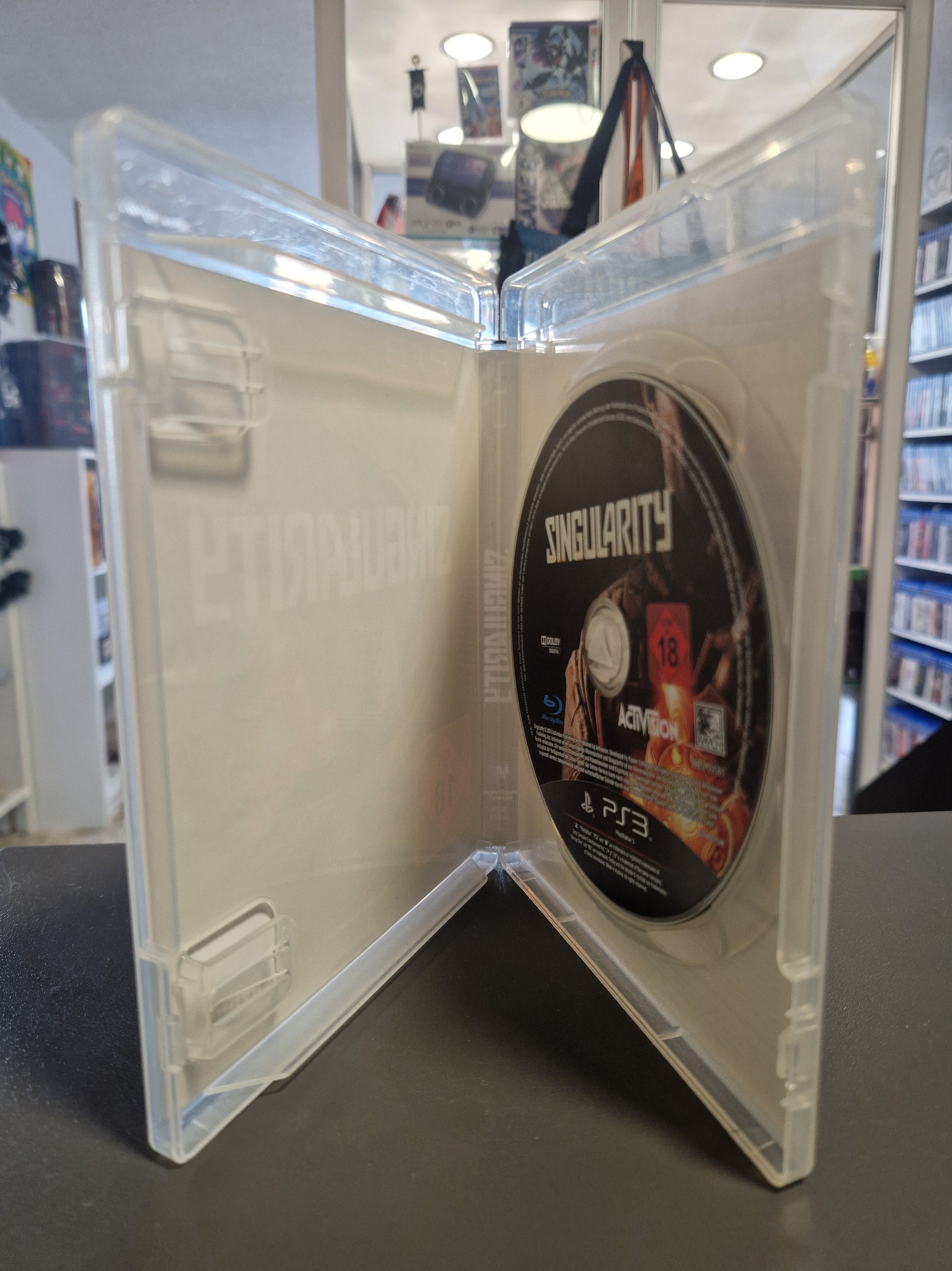 Die geöffnete, transparente PS3 Hülle zeigt die absolut saubere, kratzerfreie Singularity Blu-ray Spieldisc auf der rechten Seite. Das linke Fach für die Spielanleitung ist leer.