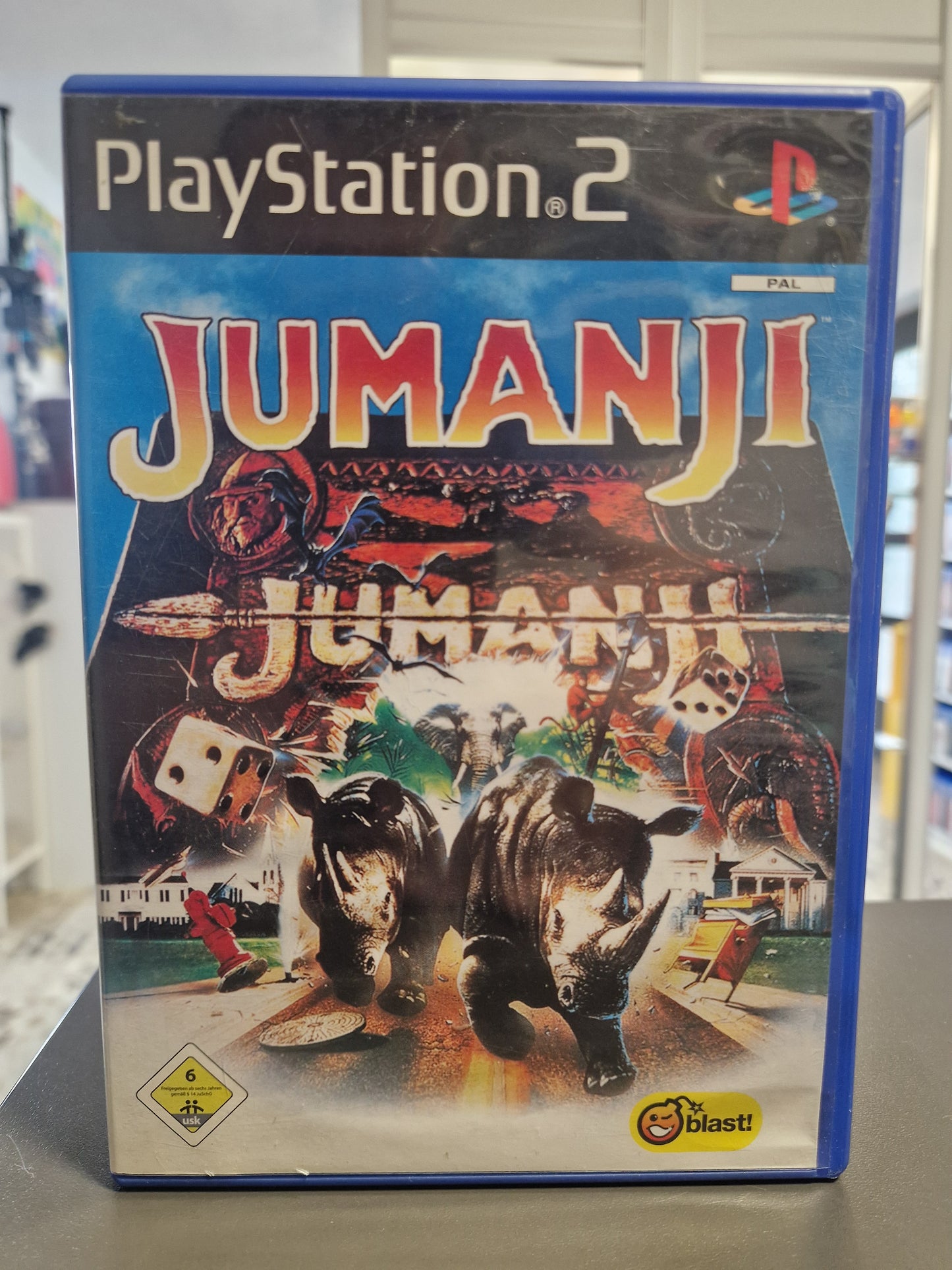 PS2-Cover von „Jumanji“ zeigt das unverkennbare Design des magischen Brettspiels mit Dschungeltieren.