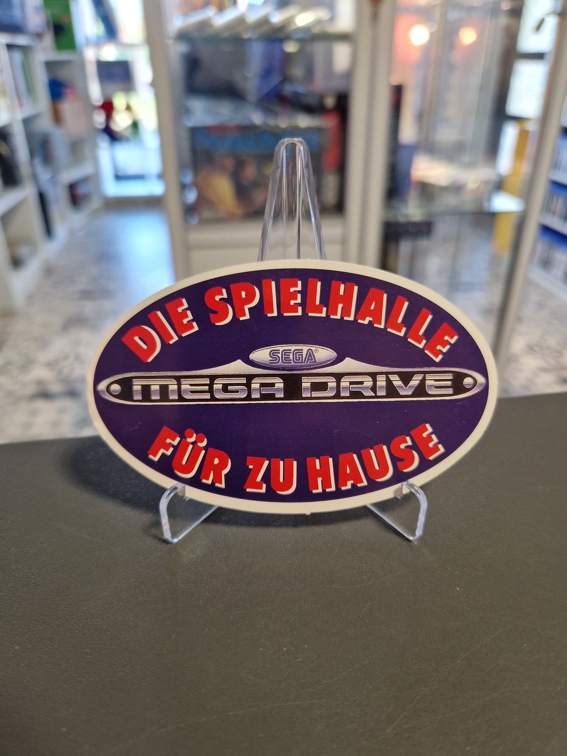 Ovaler Vintage SEGA Mega Drive Sticker in Blau/Lila mit dem Slogan „Die Spielhalle für zu Hause“