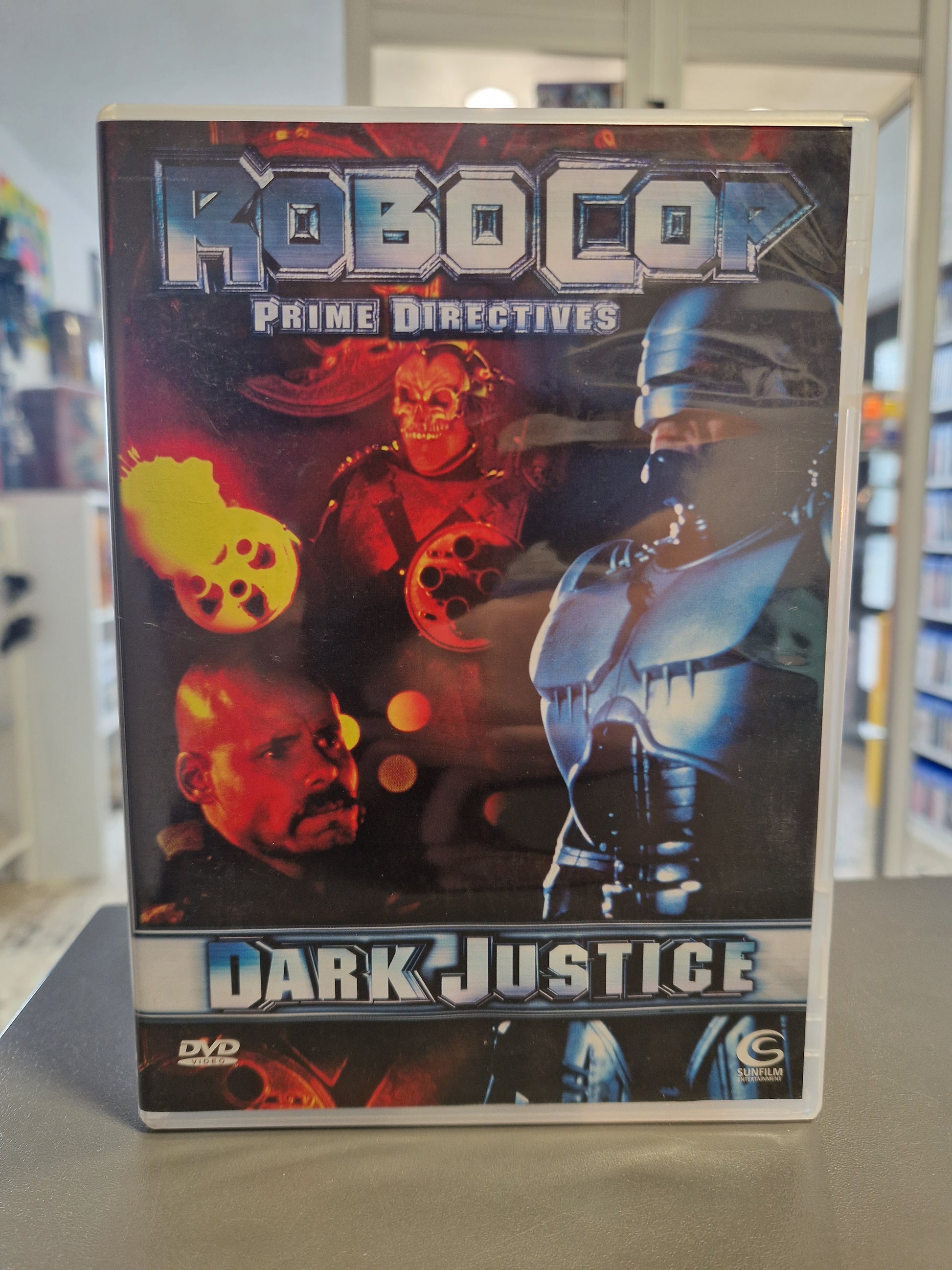 Cover von „RoboCop: Prime Directives - Dark Justice“ zeigt den legendären stählernen Cyborg-Polizisten mit gezogener Waffe vor einer futuristischen Kulisse.