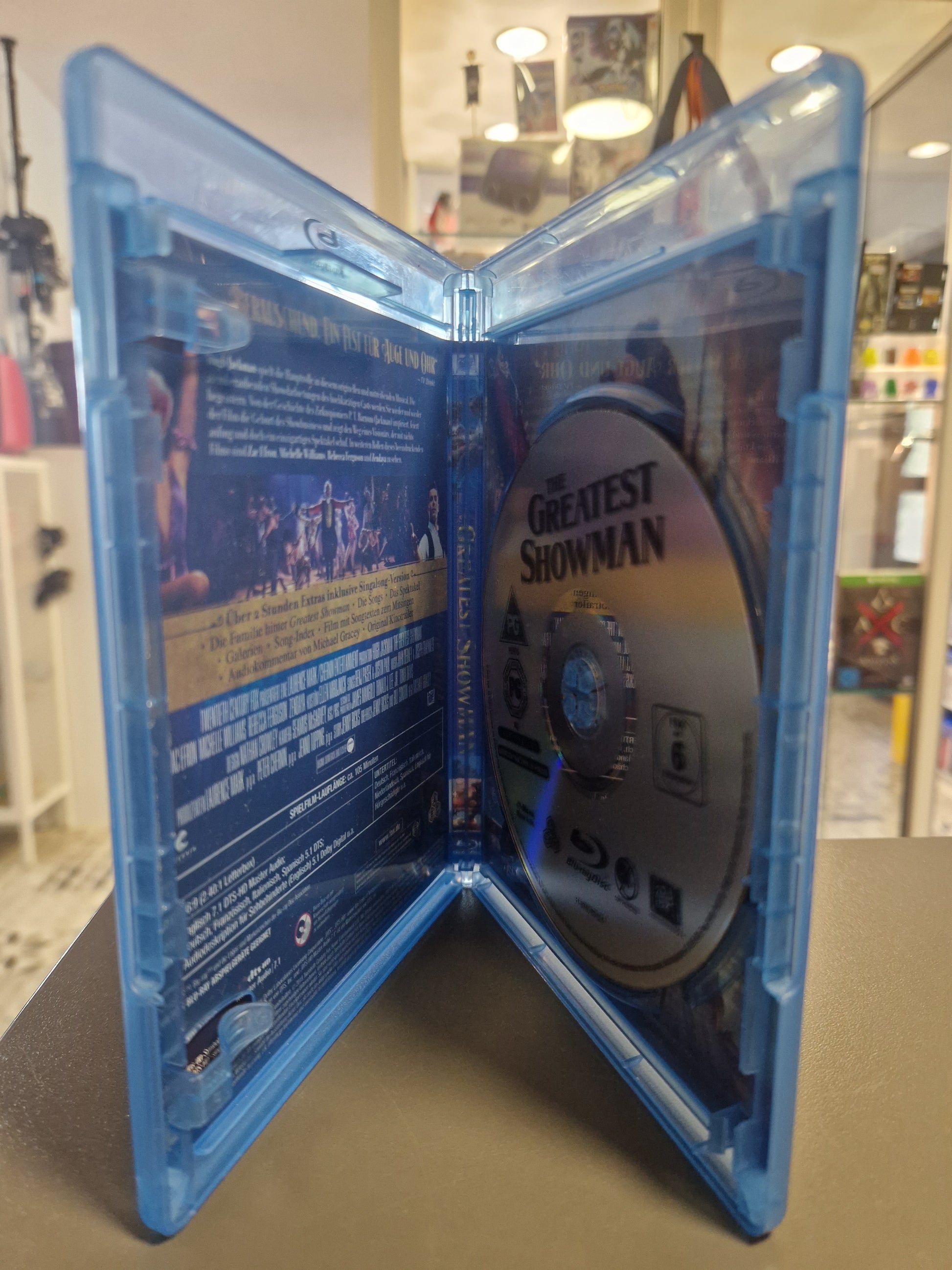 Geöffnete Blu-ray Hülle von The Greatest Showman mit Blick auf die kratzerfreie Blu-ray Disc und das Film-Motiv der Innenseite.
