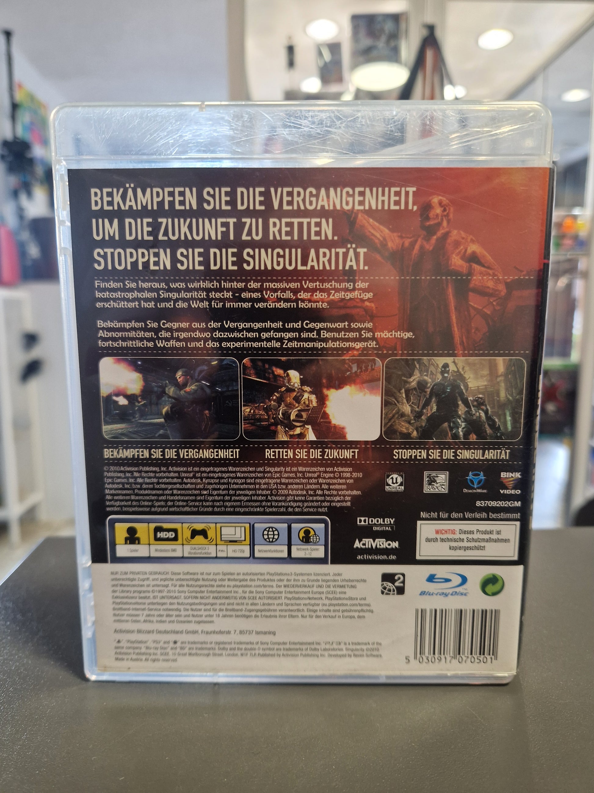 Die Rückseite der PS3 Verpackung von Singularity mit dem großen Slogan Bekämpfen Sie die Vergangenheit, um die Zukunft zu retten. Zu sehen sind drei Gameplay-Screenshots und der Barcode.
