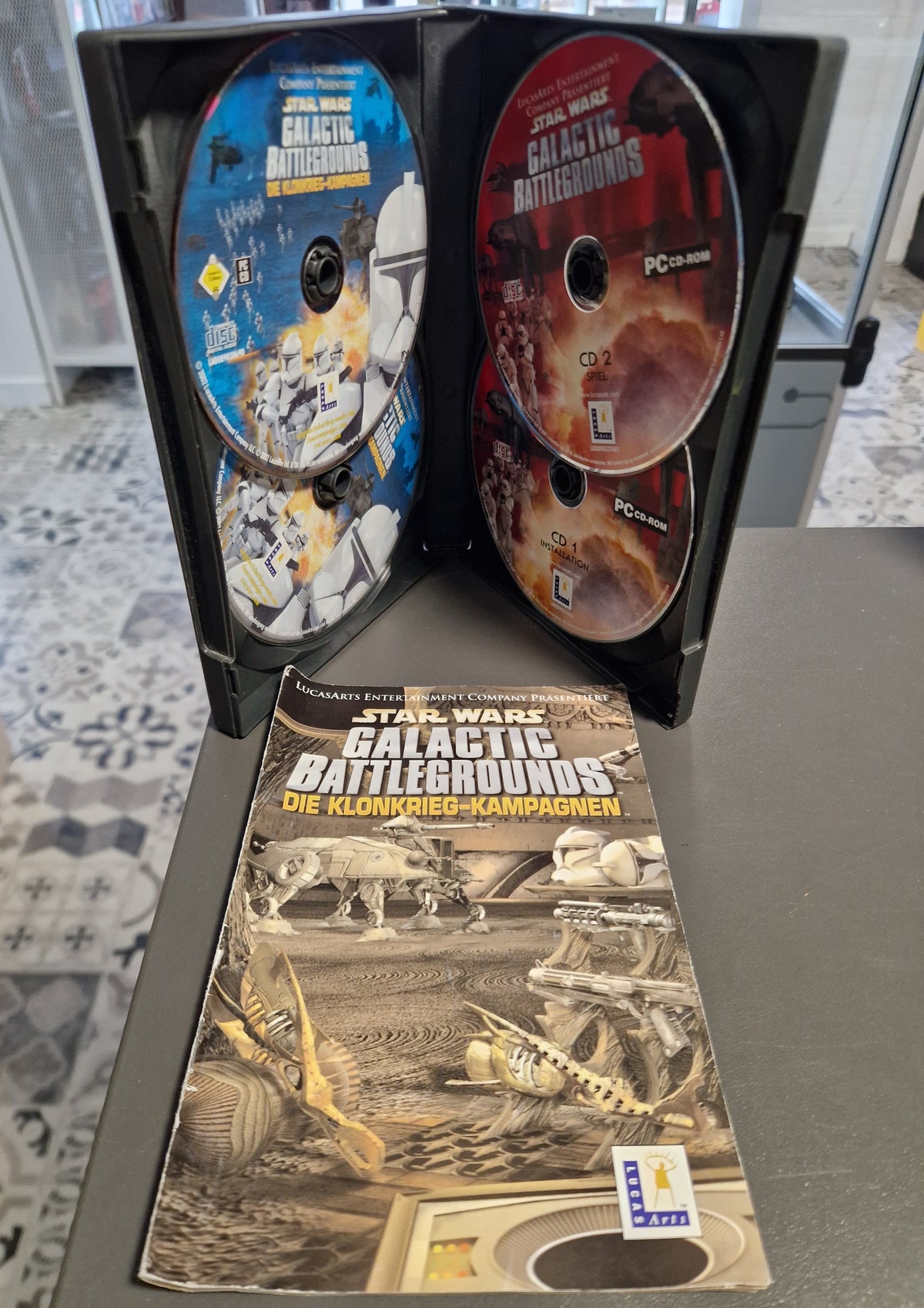 Geöffnete PC Hülle von Star Wars Galactic Battlegrounds Saga mit 3 CDs und Handbuch.
