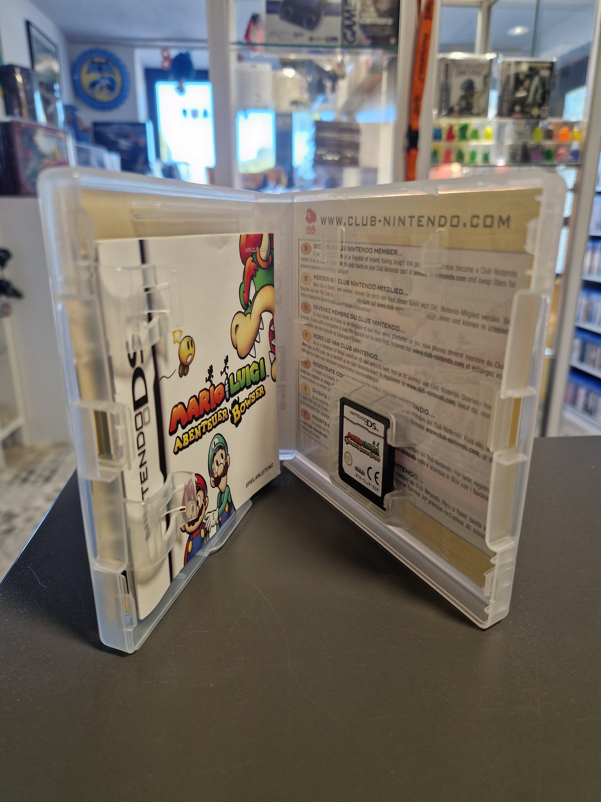 Geöffnete DS-Hülle mit dem Top-Modul, der Anleitung und der Nintendo Club Karte.