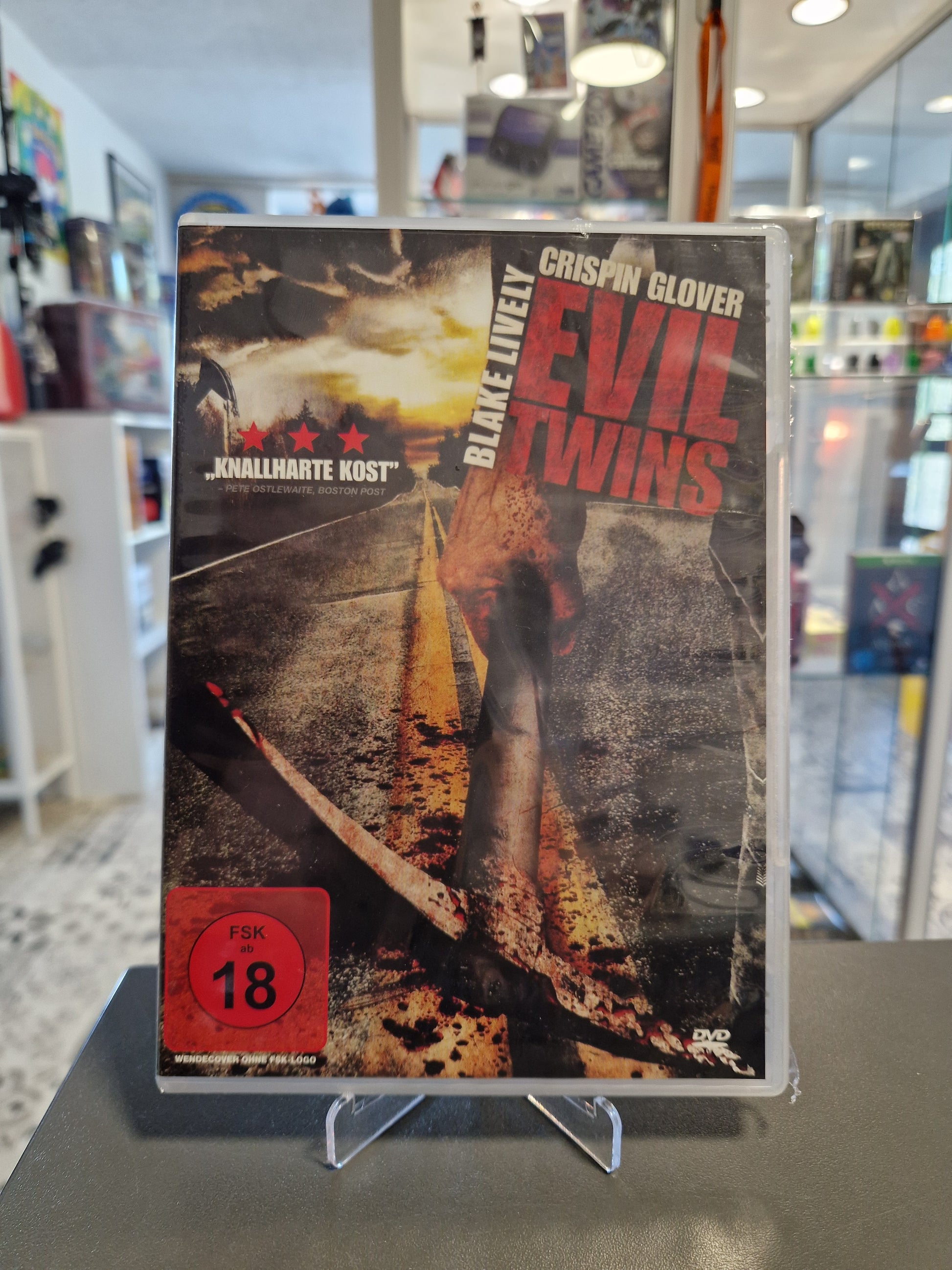 Neu und originalverpackte DVD des Horrorfilms Evil Twins mit FSK 18 Freigabe. Das Cover zeigt eine blutige Spitzhacke auf einer einsamen Landstraße und nennt die Darsteller Blake Lively und Crispin Glover.