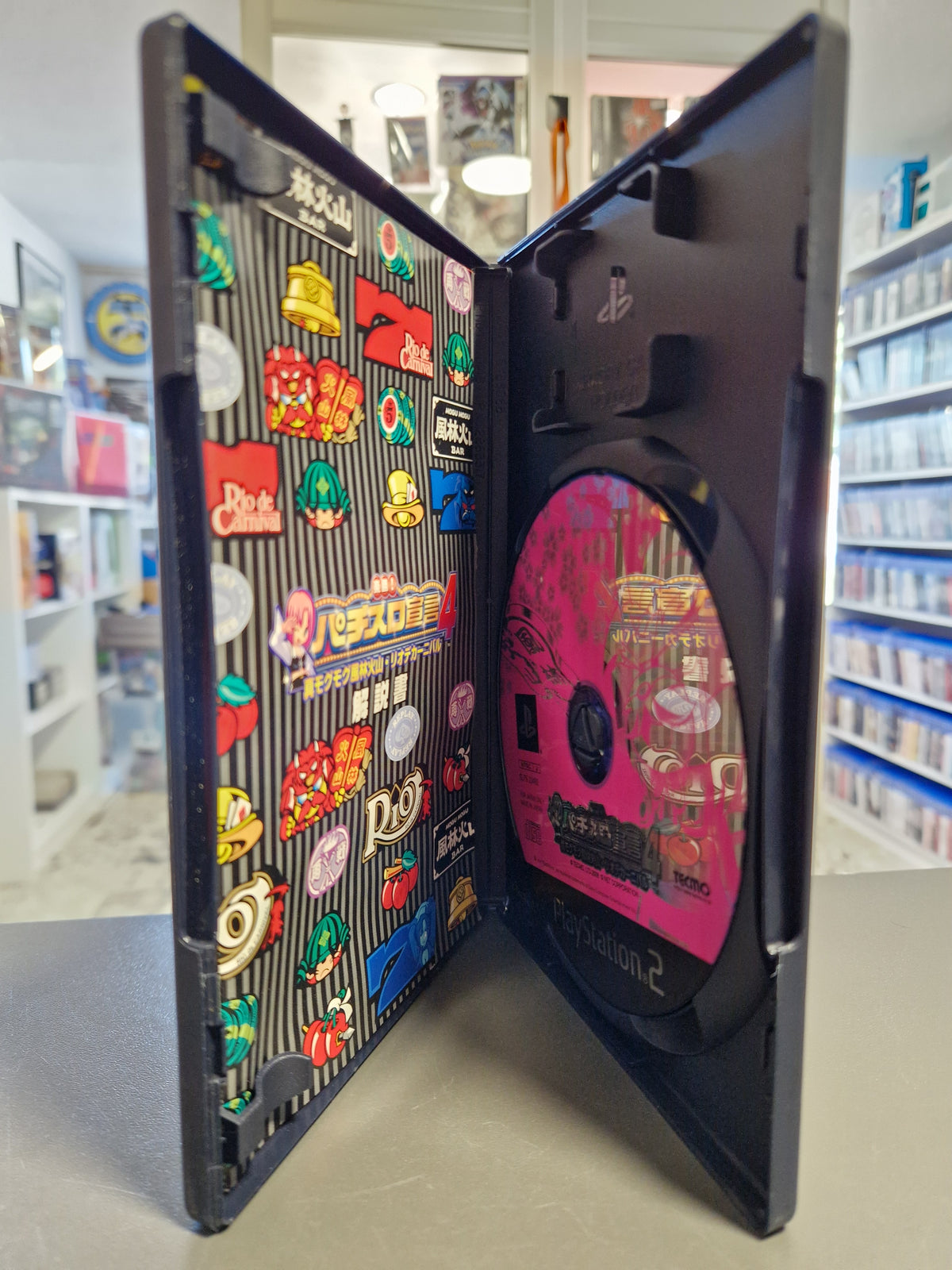 Geöffnete PS2 Hülle von Rakushou Pachi-Slot Dekasou 4 NTSC-J mit pinker Disc und japanischer Anleitung.