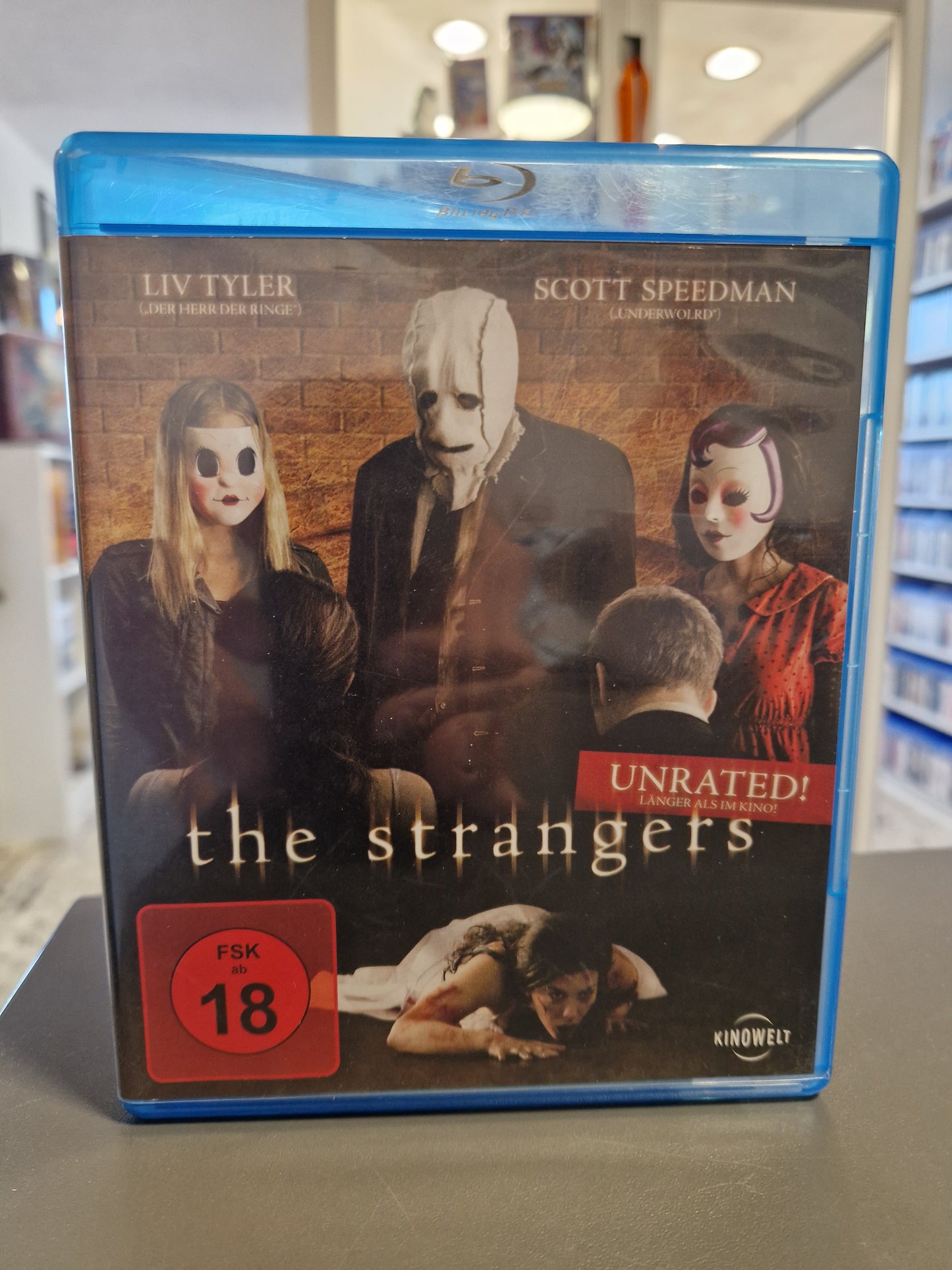 The Strangers Cover mit den ikonischen Masken der Angreifer und Hauptdarstellerin Liv Tyler.
