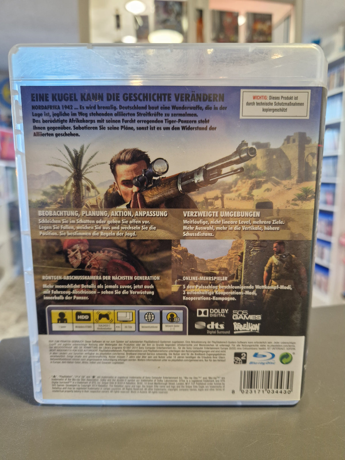 Rückseite der PS3 Hülle von Sniper Elite III mit Beschreibung der Röntgen-Abschusskamera und Barcode 8023171034430.