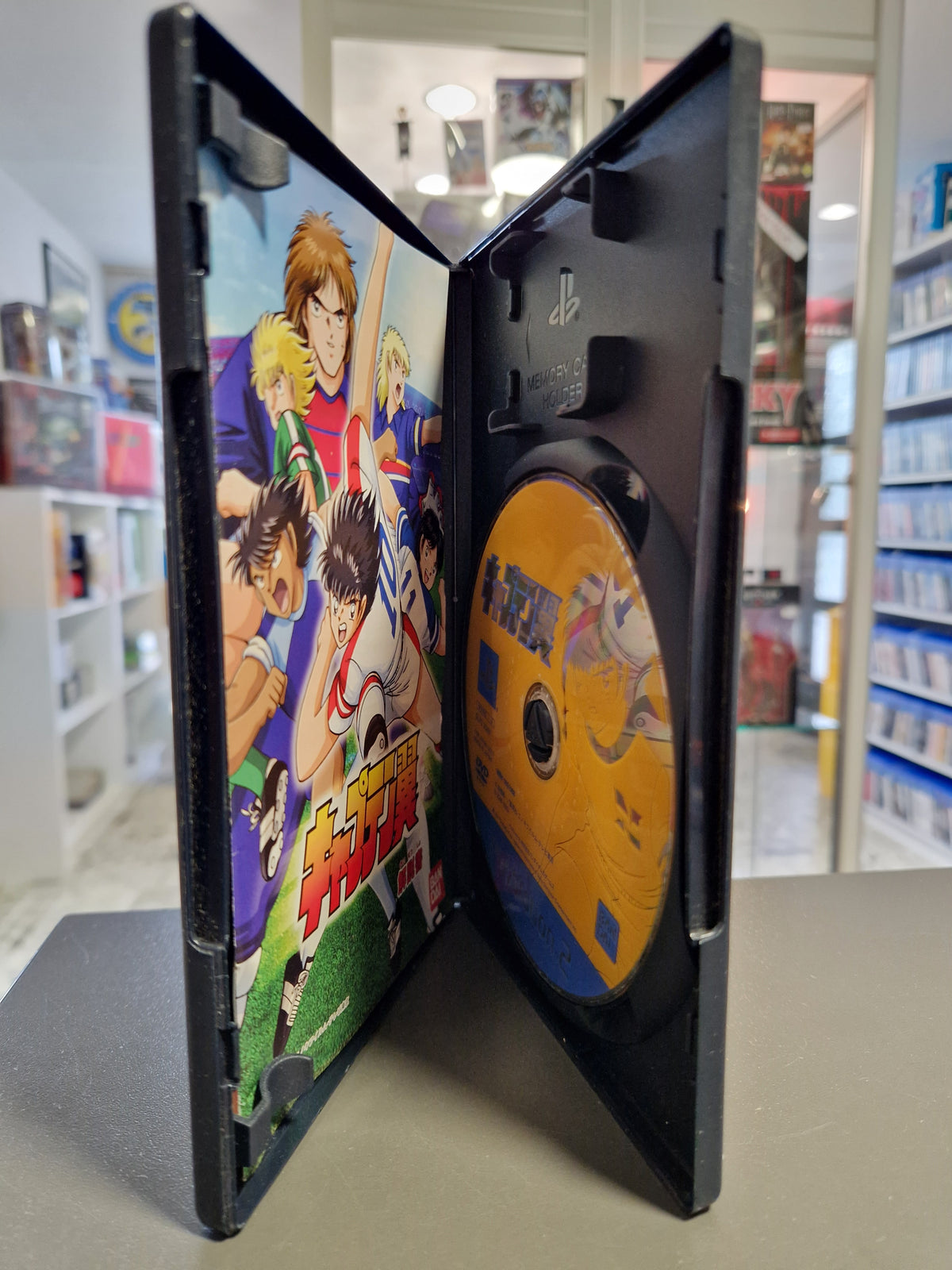 Geöffnete PS2 Hülle von Captain Tsubasa mit Disc und gedruckter japanischer Anleitung.