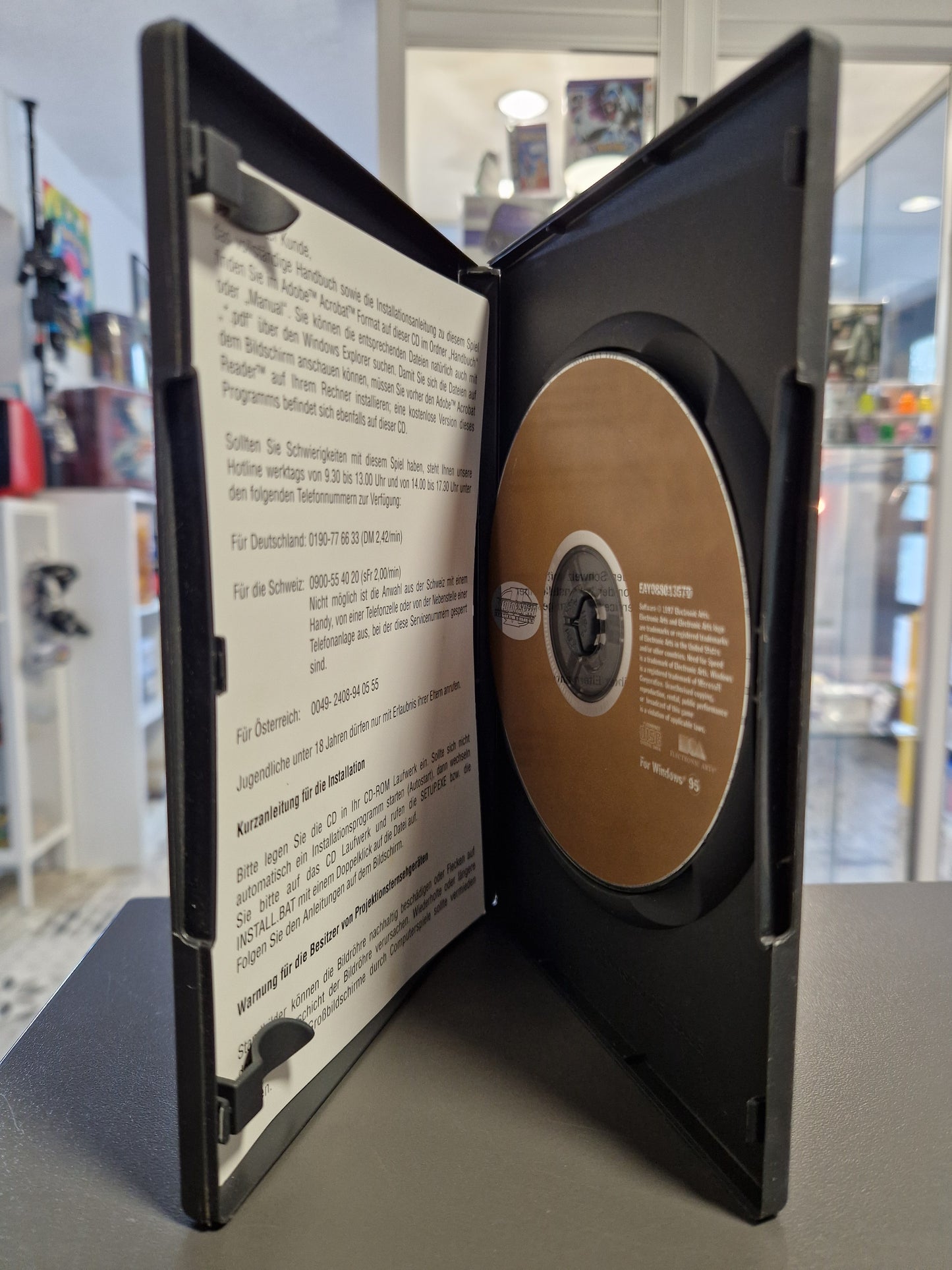 Geöffnete Hülle mit der goldfarbenen Spiele-CD und den Installationshinweisen.
