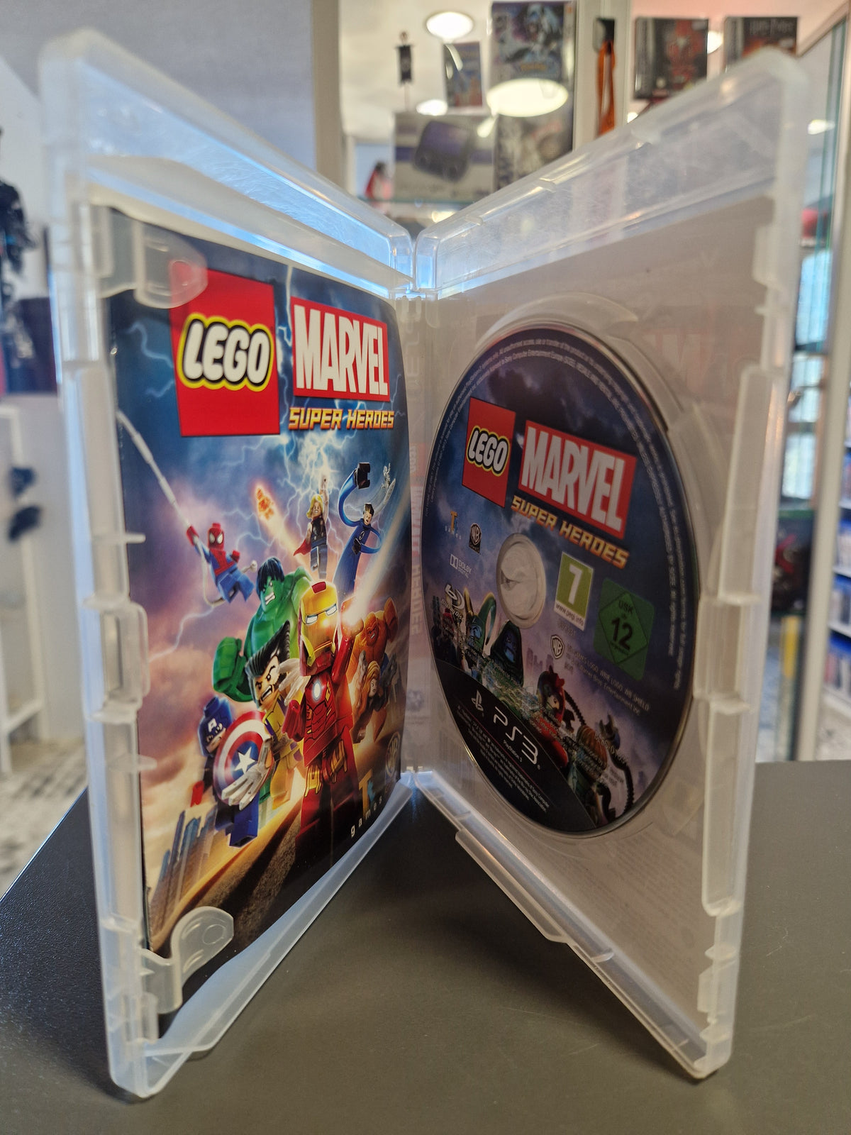 Geöffnete PS3 Hülle von LEGO Marvel Super Heroes mit Disc und Handbuch.