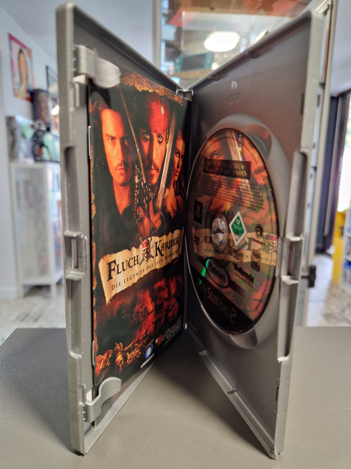 Geöffnete PS2 Platinum Hülle von Fluch der Karibik mit DVD-ROM und Anleitungsheft.