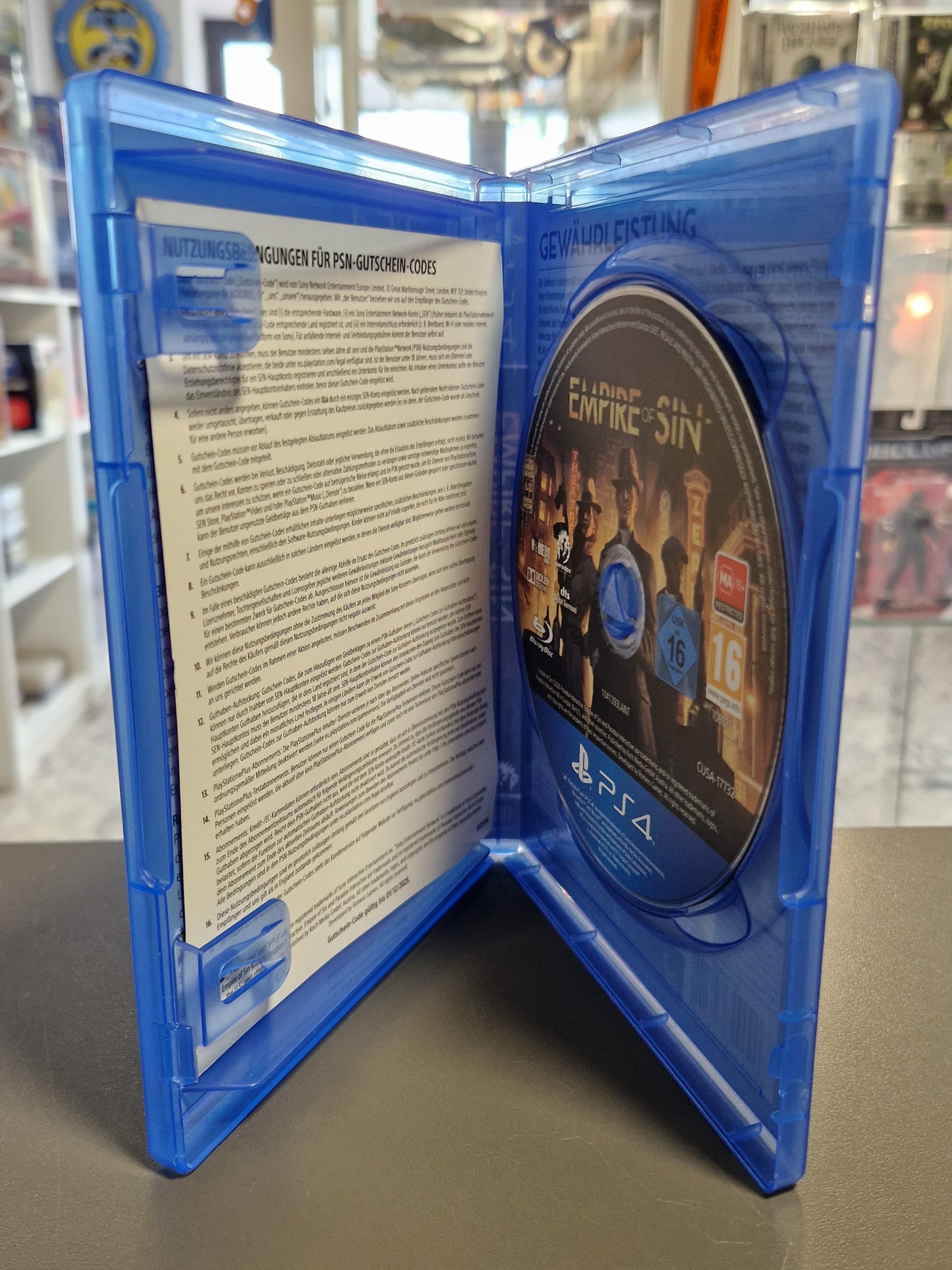 geöffnete blaue PS4-Hülle mit der sauberen, originalen Spiele-Disc auf der rechten Seite und dem unbeschädigten Beilagenzettel.